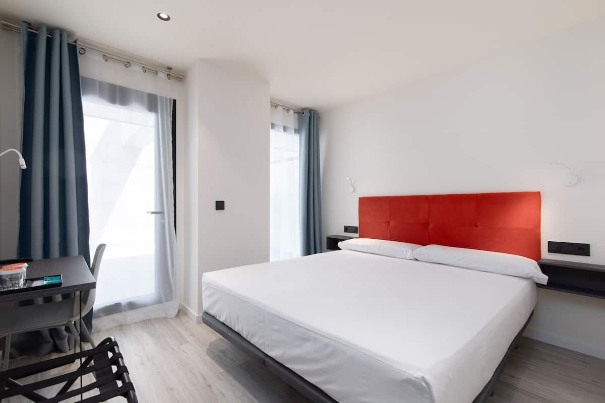 Una habitación de hotel moderna con una cama, un escritorio y una silla.