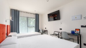 Een hotelkamer met twee bedden, een bureau, een stoel, een televisie en een raam met gordijnen.