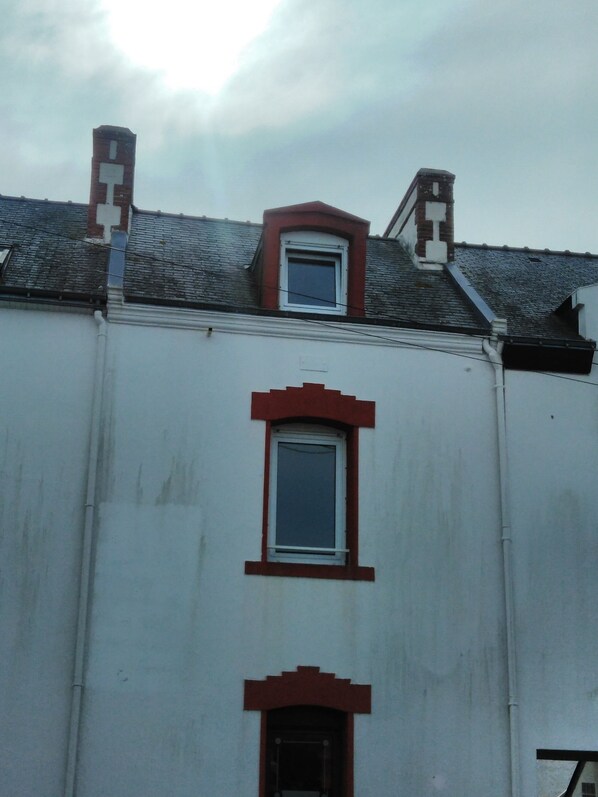 A building with a red-framed window, a small dormer window, and a chimney.
