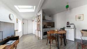 A modern apartment with a dining area, kitchen, and a TV in the living room.