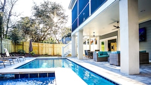 Une piscine dotée d’un patio couvert, de mobilier d’extérieur et d’une clôture en bois.