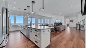 A spacious kitchen with a large island, white cabinetry, and pendant lighting. - Another Round by GSVR | Beachfront w/ Pool & Elevator | Free Activities/Golf (Gulf Shores)