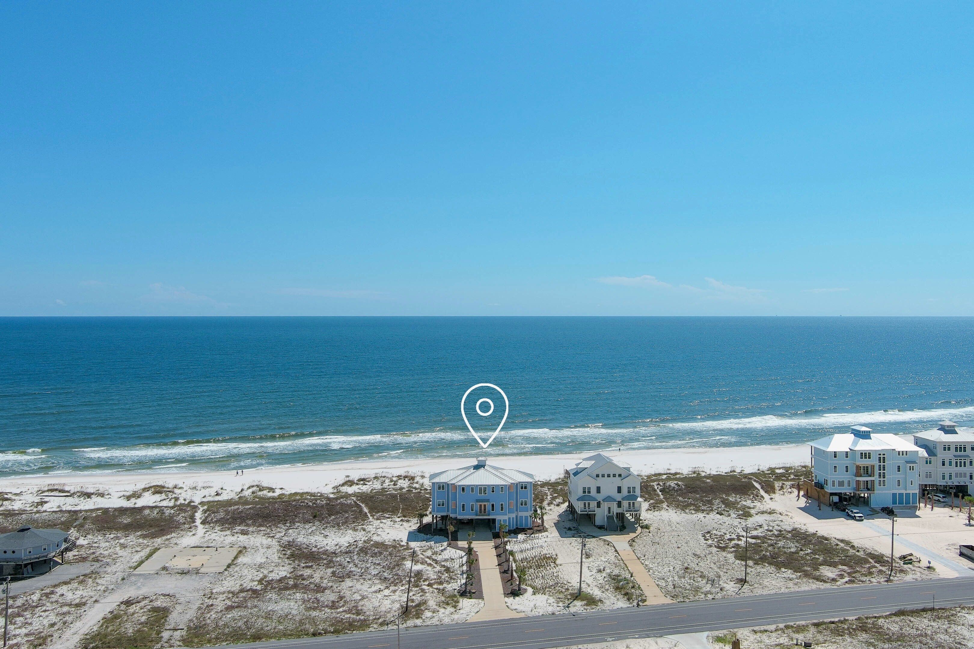A beachfront property with a central building and two smaller structures, connected by pathways.