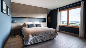 A modern bedroom with a large bed, a desk, and a view of the sea. - Au NEUF MILLE, luxury apartment **** 2 steps from the port of Perros-Guirec (Perros-Guirec)