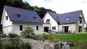 A two-story house with a sloped roof, a stone retaining wall, and a small pond in the front yard. - Au NEUF MILLE, luxury apartment **** 2 steps from the port of Perros-Guirec (Perros-Guirec)