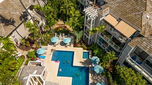 An aerial view of a resort with a central swimming pool, multiple lounge areas, and surrounding lush greenery. - Private and Sweet Wailea 1 BD+2 BA Grand Champions Villa (Wailea)