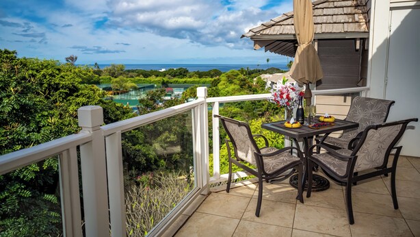 A balcony with a table and chairs, overlooking a lush landscape and a golf course. - Private and Sweet Wailea 1 BD+2 BA Grand Champions Villa (Wailea)