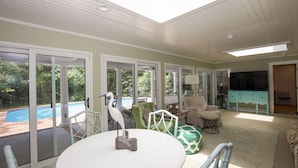 A sunlit room with a pool view, a dining table, and a teal-colored cabinet. - 4 Bedroom Pinehurst Home with Pool and Hot Tub (Pinehurst)