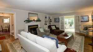 A living room with a fireplace, white sofas, a coffee table, and a dining area with chairs and a table. - 4 Bedroom Pinehurst Home with Pool and Hot Tub (Pinehurst)