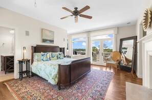 Ein Schlafzimmer mit einem großen Bett, einem Deckenventilator, Blick ins Freie und einem Balkon.