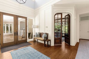 A spacious entryway with a bench, a rug, and a view into a room with a door.