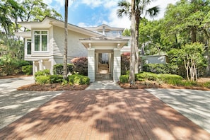 A two-story house with a front porch, a driveway, and surrounding greenery. - Stunning home close to the Ocean Course (Johns Island)