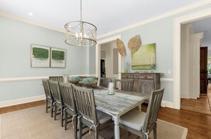 A dining room with a wooden table, chairs, and a chandelier. - Stunning home close to the Ocean Course (Johns Island)