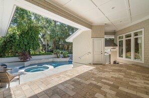 A spacious outdoor area with a swimming pool, a covered patio, and a view of a residential building. - Stunning home close to the Ocean Course (Johns Island)