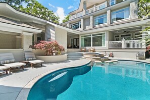 Une maison moderne dotée d’une piscine, d’un espace salon extérieur et d’un patio couvert.