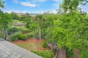 A lush garden with a wooden deck and a view of a distant building. - Stunning home close to the Ocean Course (Johns Island)