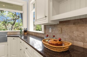A kitchen with white cabinetry, a granite countertop, and a view of trees outside. - Stunning home close to the Ocean Course (Johns Island)