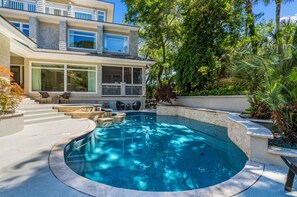 Ein modernes Haus mit Swimmingpool, Sitzgelegenheiten im Freien und einem großen Fenster mit Blick auf den Garten.