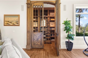 A wooden bookshelf with a ladder, a potted plant, and a painting on the wall. - Stunning home close to the Ocean Course (Johns Island)
