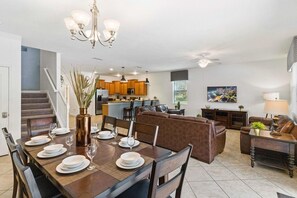 A dining area with a table set for four, a sofa, and a kitchen in the background.