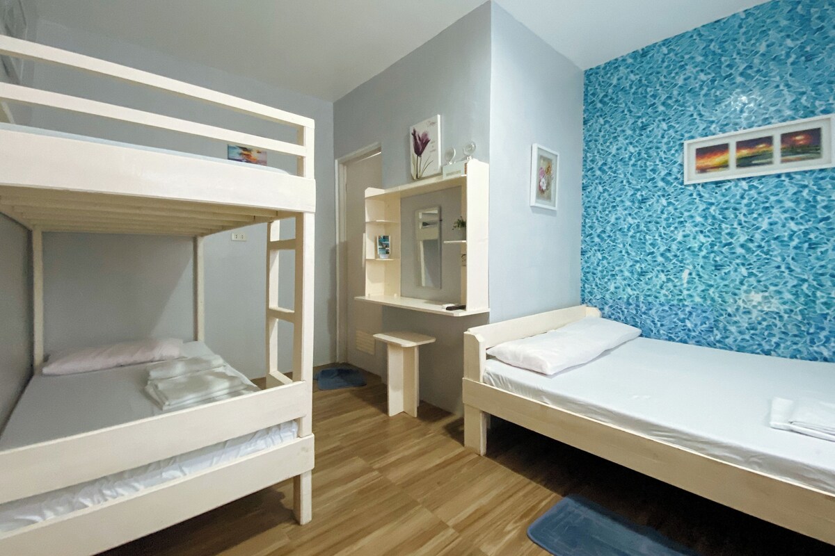 A room with bunk beds, a desk, a mirror, and a blue textured wall.