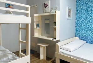 Una habitación con literas, un escritorio con espejo y una cama.