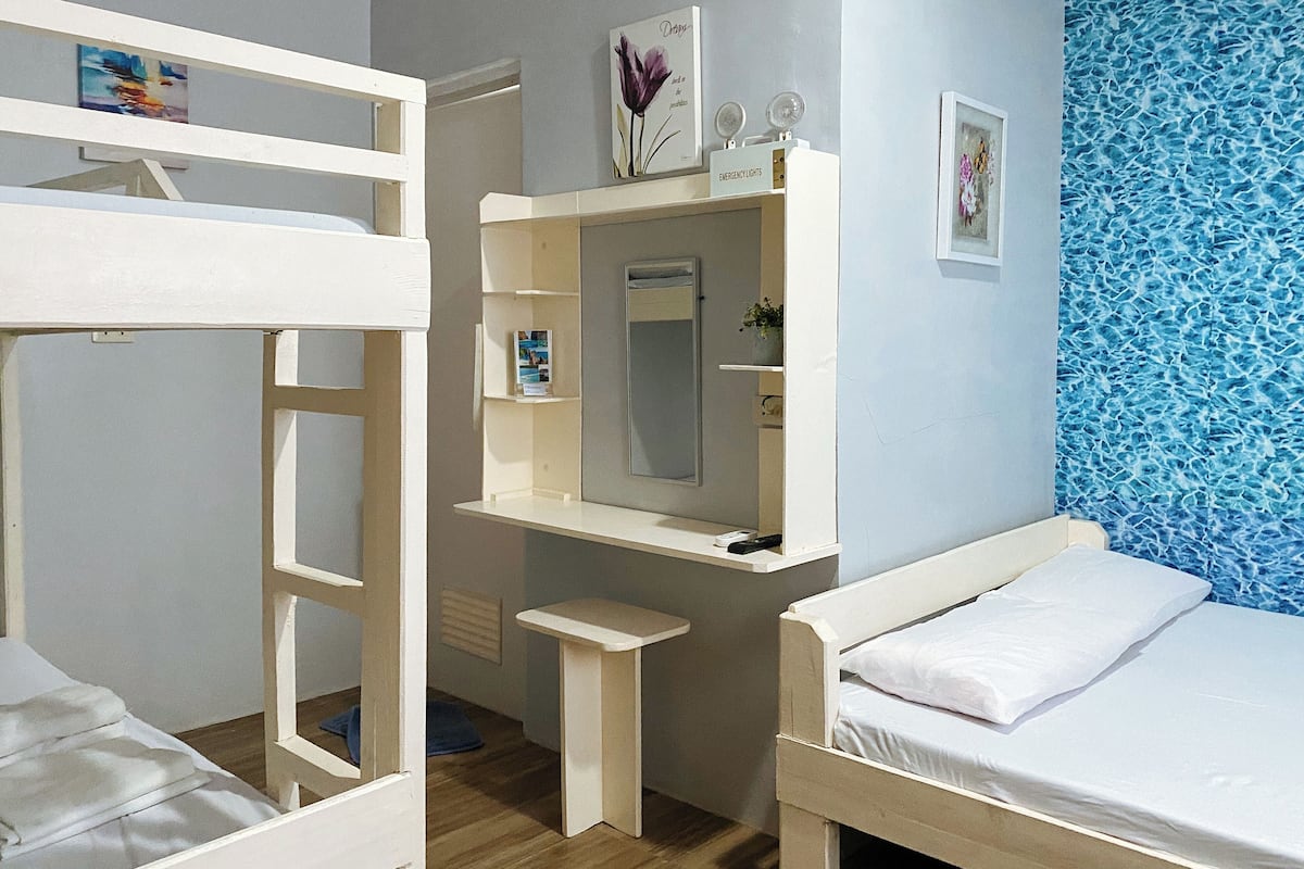 Une chambre avec des lits superposés, un bureau avec un miroir et un lit.