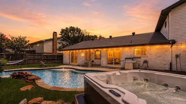 A backyard with a swimming pool, hot tub, and outdoor seating area.