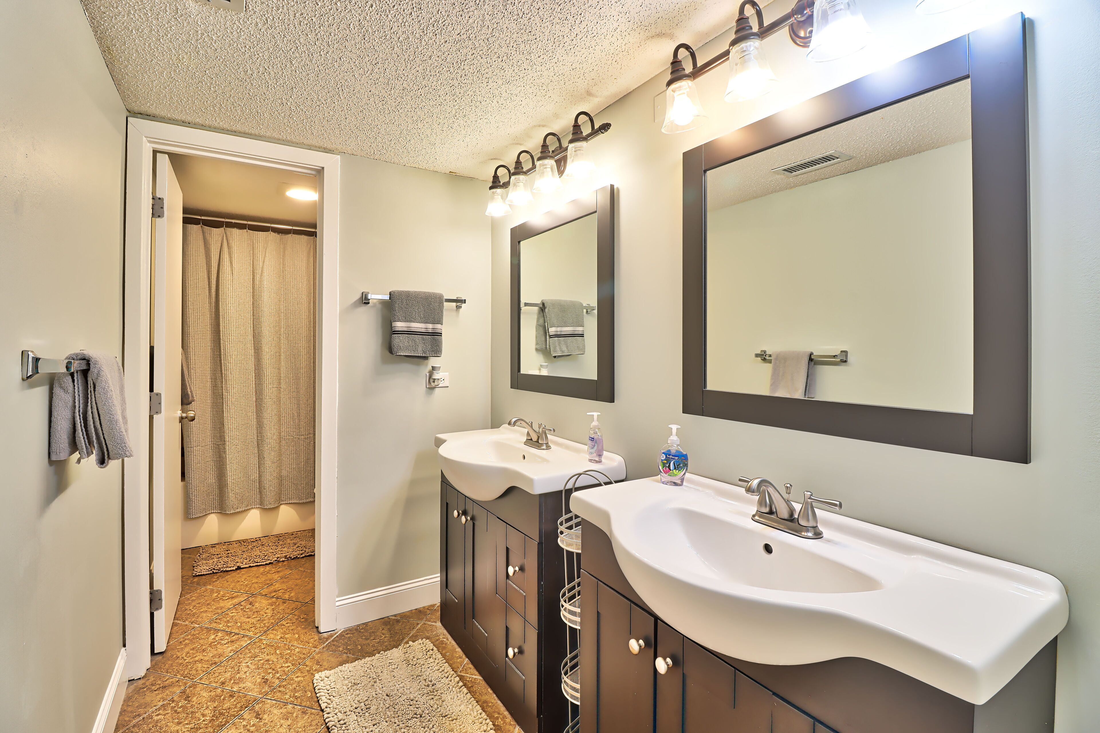 A bathroom with two sinks, a large mirror, and a shower curtain.