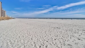 A wide sandy beach with footprints, a clear sky, and a distant view of the ocean. -  Golfers Welcome, South Tower-Ocean Creek-1st Floor-Spacious Condo,Openings (Myrtle Beach)