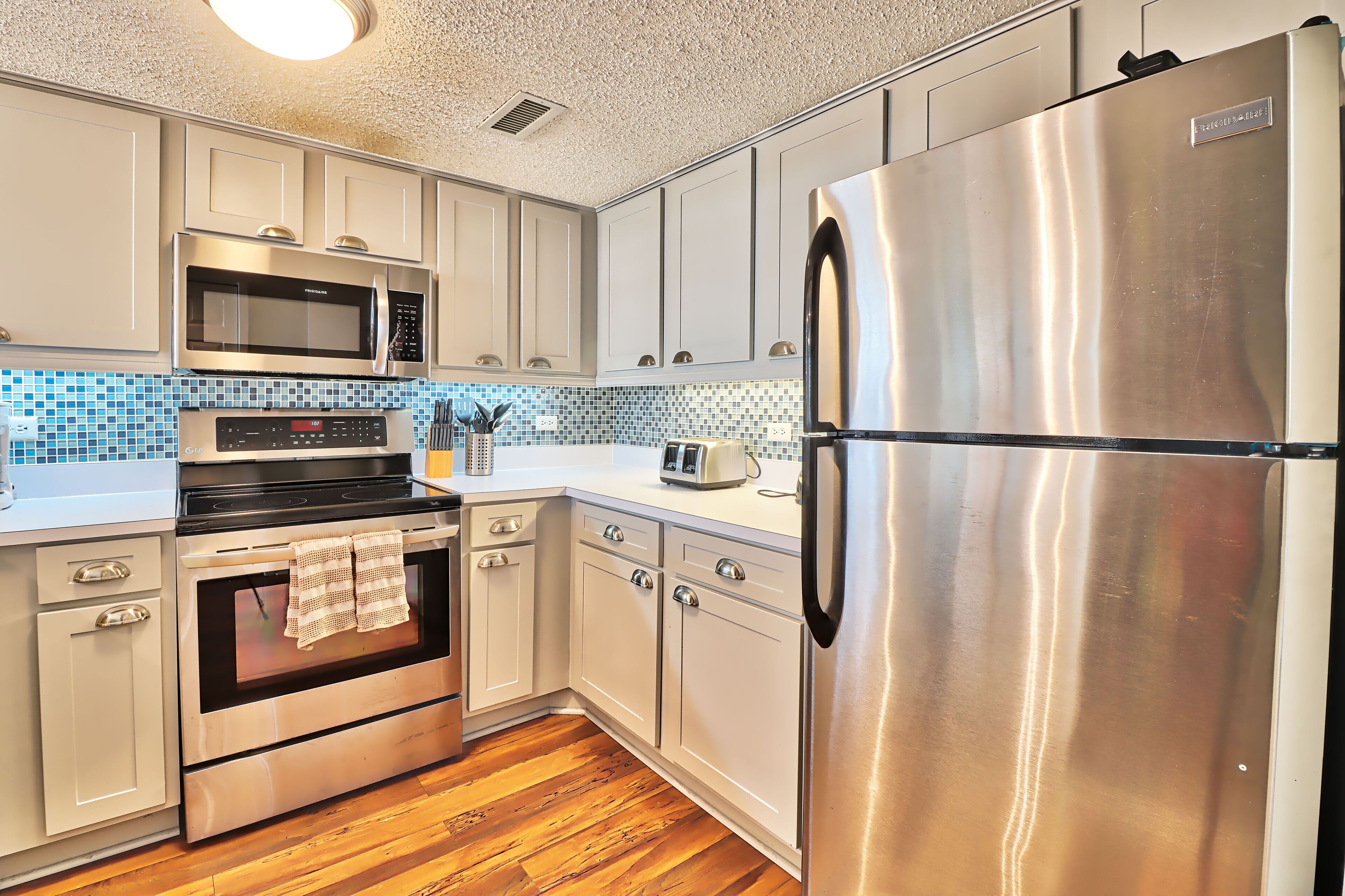 A modern kitchen with stainless steel appliances, a microwave, oven, and a refrigerator.