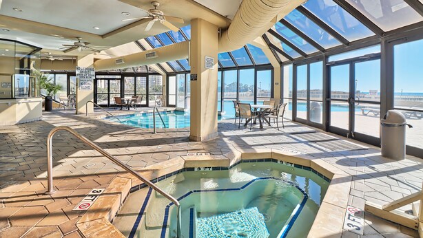 An indoor swimming pool area with clear glass walls, a hot tub, and a seating area with a view of the beach. -  Golfers Welcome, South Tower-Ocean Creek-1st Floor-Spacious Condo,Openings (Myrtle Beach)
