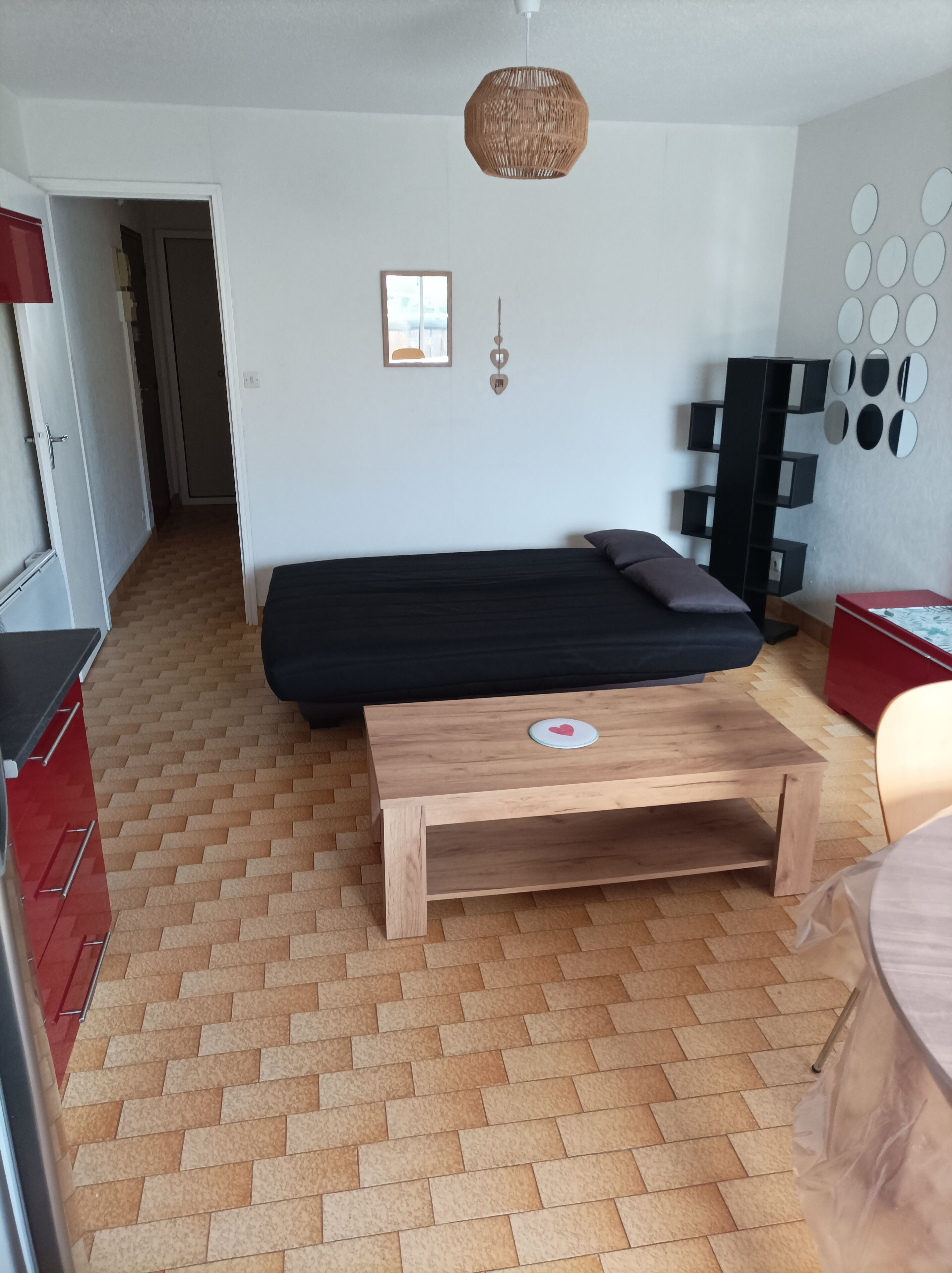 Une chambre à coucher comprenant un lit, une table de chevet en bois, un luminaire suspendu, une armoire et un mur recouvert d’un miroir.