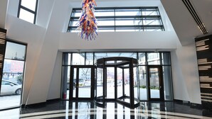 En rymlig entréhall med högt i tak, stora fönster och en central, roterande dörr.