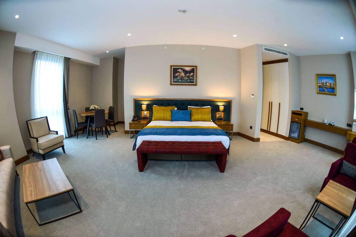 A hotel room with a large bed, bedside tables, a desk, and a chair.