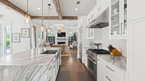 A modern kitchen with marble countertops, wooden beams, and pendant lighting. - Family Retreat with Pool and Golf Cart (Watersound)