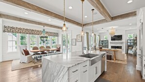 A spacious kitchen with a large island, wooden beams on the ceiling, and a dining area with a table and chairs. - Family Retreat with Pool and Golf Cart (Watersound)