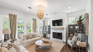 A spacious living room with a large sofa, a coffee table, and a fireplace. - Family Retreat with Pool and Golf Cart (Watersound)