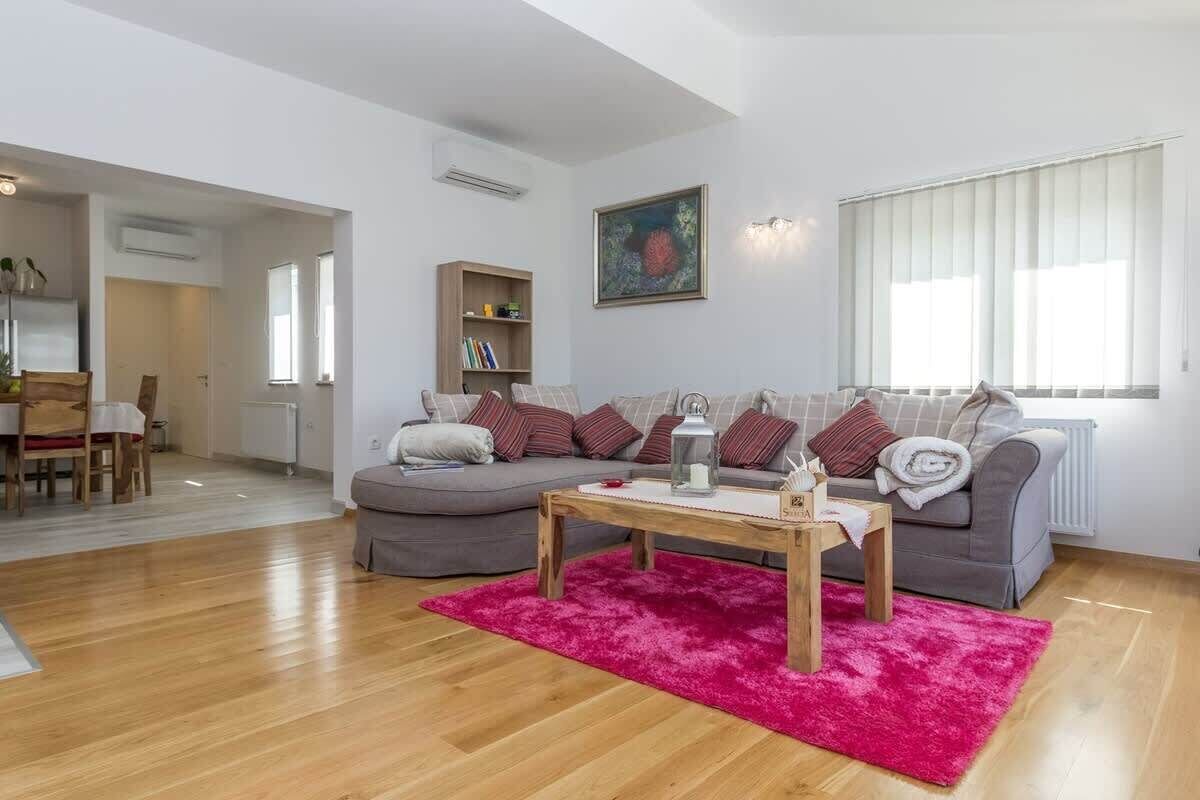Ein Wohnzimmer mit einer Couch, einem Couchtisch, einem roten Teppich und einem Bücherregal.