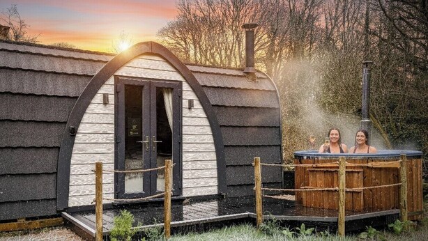 A rustic cabin with a wooden hot tub, a chimney, and a wooden deck. - Emlyn's Coppice - Woodland Glamping (Holywell)