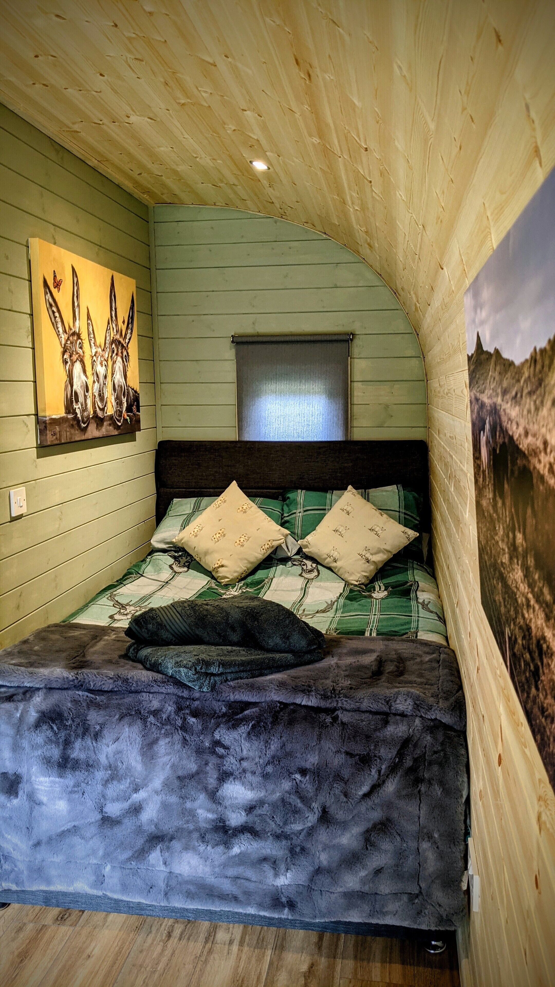 Ein gemütliches Schlafzimmer mit gewölbter Decke, einem Bett mit gemusterten Betttextilien, einem Bild an der Wand und einem Fenster mit Blick.