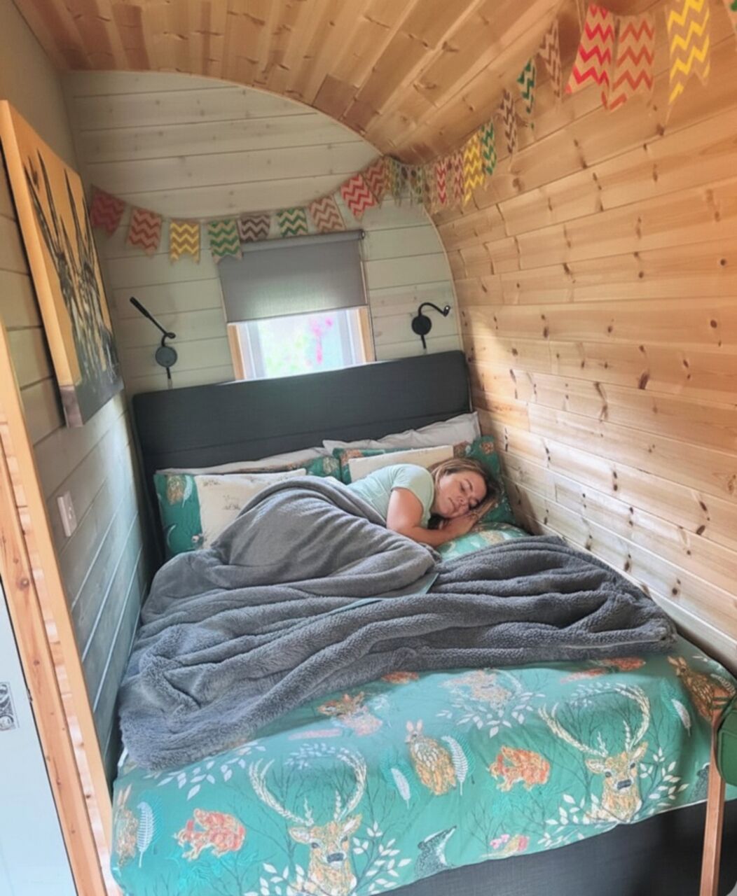Una habitación acogedora con techo curvo, cama con colcha estampada y pared decorada con motivos de zigzag coloridos.
