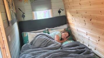 Una habitación acogedora con techo curvo, cama con colcha estampada y pared decorada con motivos de zigzag coloridos.