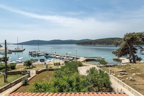 Un port de plaisance avec des bateaux amarrés, une jetée s’avançant dans l’eau et, au loin, un paysage vallonné.