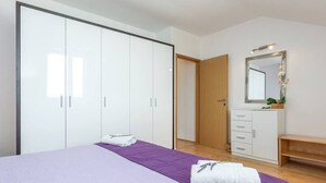 A bedroom with a bed, a wardrobe, a mirror, and a bench. - Beachfront Holiday House Zita (Brgulje)