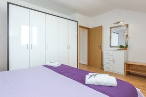 Et soveværelse med seng, garderobe, spejl og bænk.