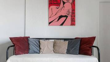 Une chambre à coucher moderne avec un lit, une table en bois et une œuvre d’art rouge accrochée au mur.