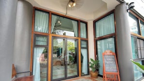 A hotel entrance with large glass doors, a chalkboard sign, and a potted plant. - Saeng Panya Home - Boutique Residence (Chiang Mai)