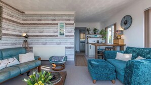 A cozy living room with a sofa, a chair, and a coffee table. There is a kitchen area with a dining table and chairs. - 1 Bed Flat - Sleeps 2 - Pets - Balcony - Parking (Looe)