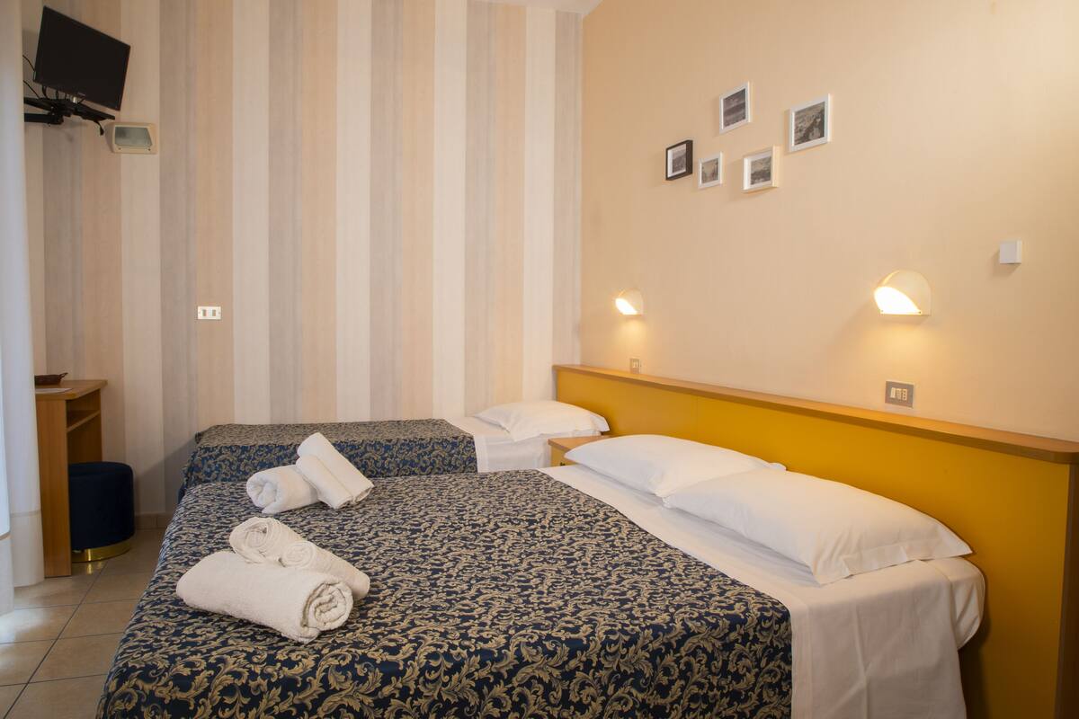 Habitación de hotel con dos camas, televisión y escritorio.